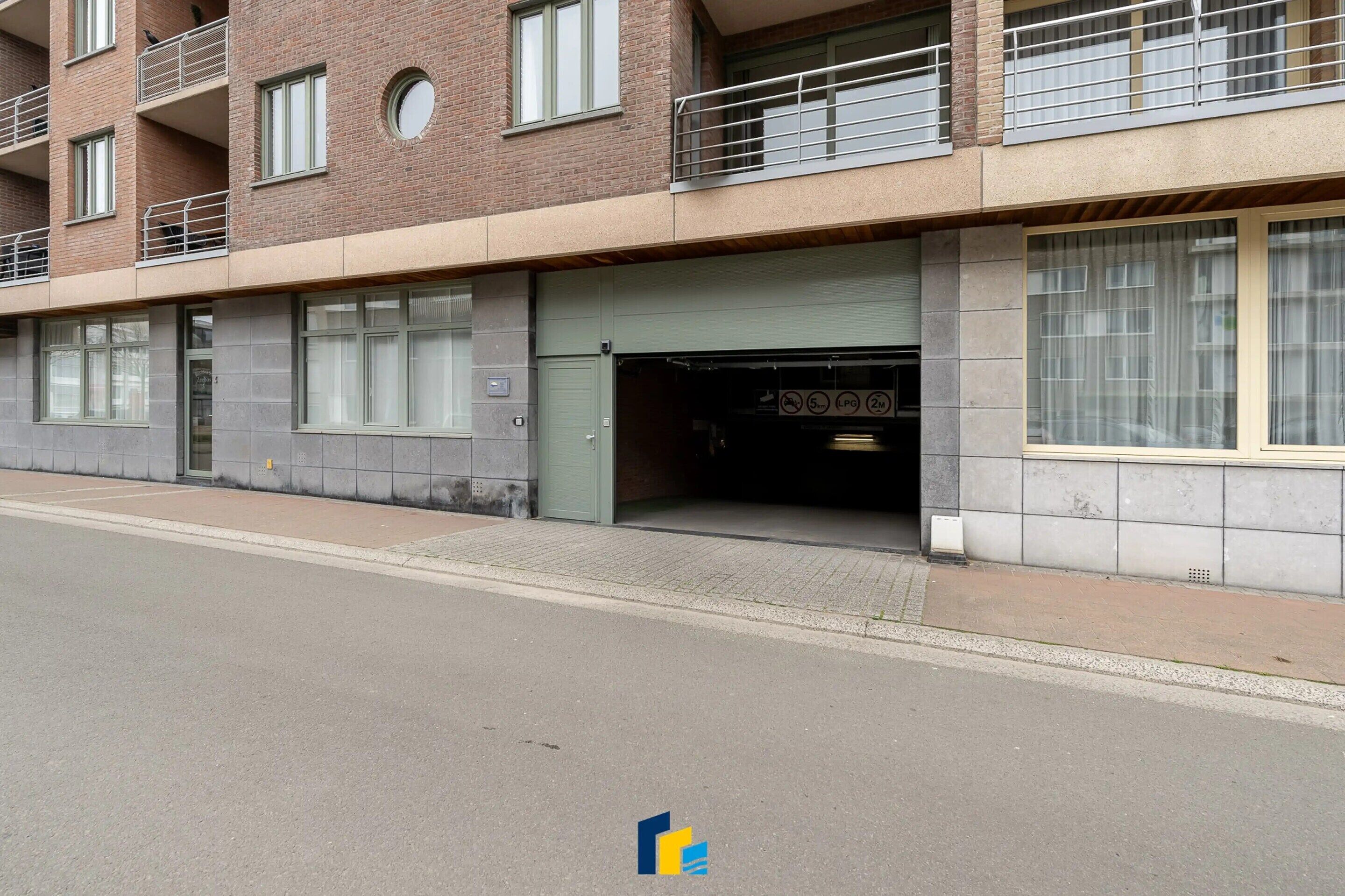 A multi-story building with a garage entrance, large windows, and a brick facade.