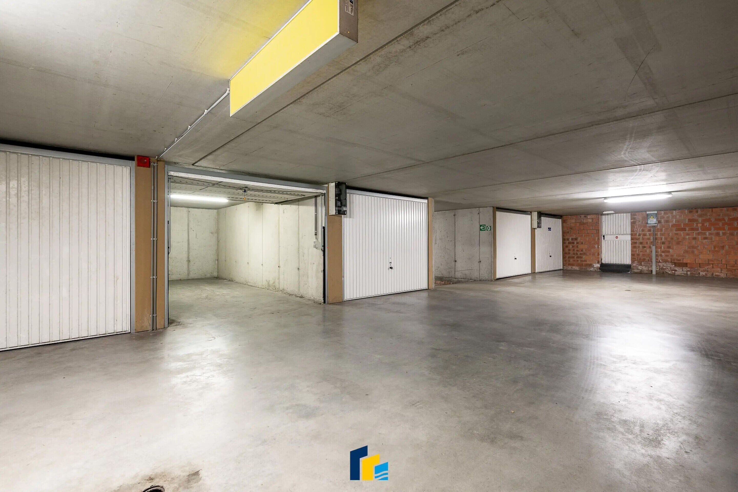 A large, empty parking garage with concrete floors and white doors.