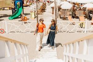 A beachside walkway with a playground, lounge chairs, and umbrellas. - Apartment in Blankenberge Near the Pier (Blankenberge)