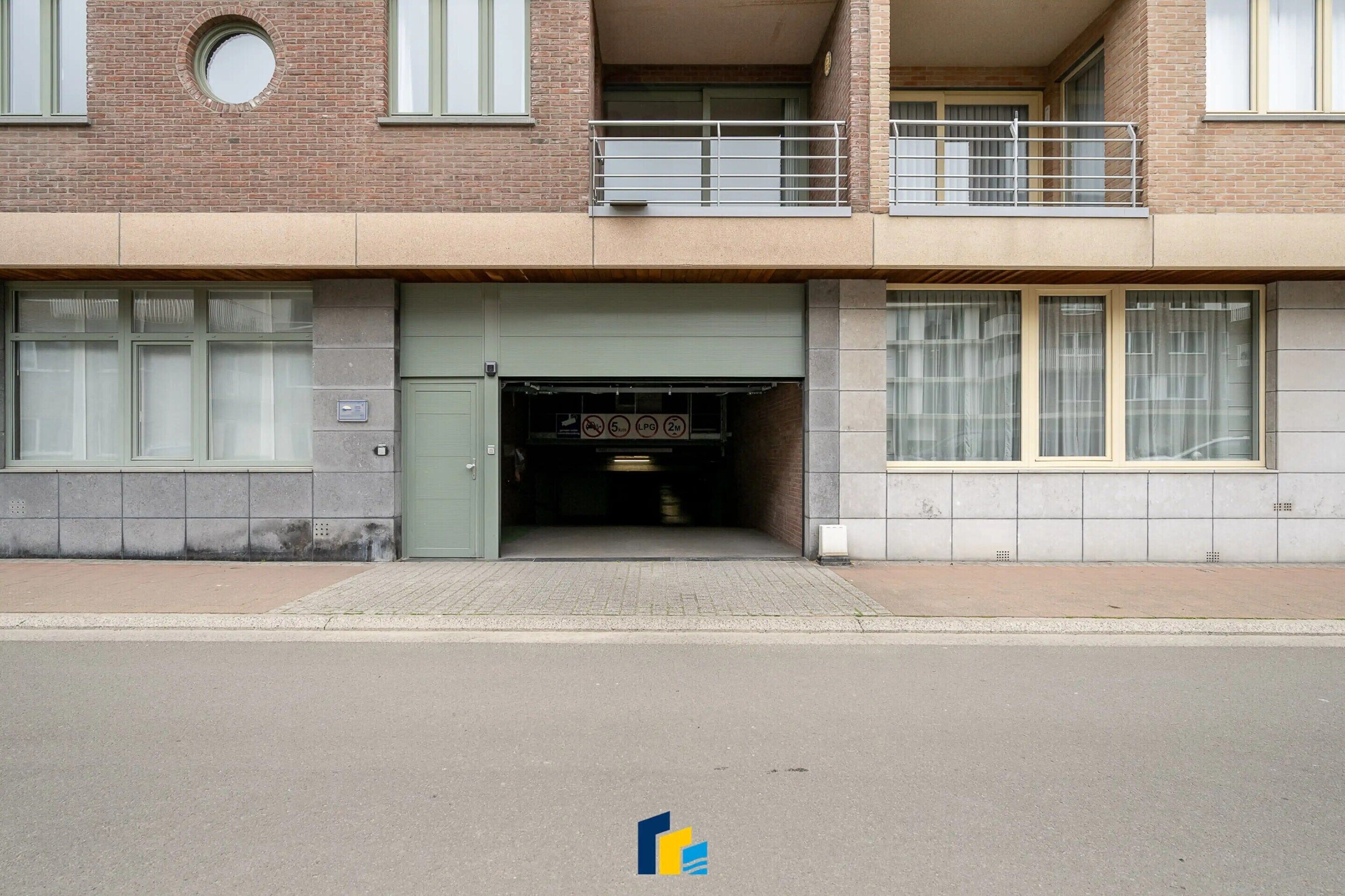 Un bâtiment à deux étages doté d’une entrée de garage, d’un balcon à l’étage supérieur et d’une façade en briques.