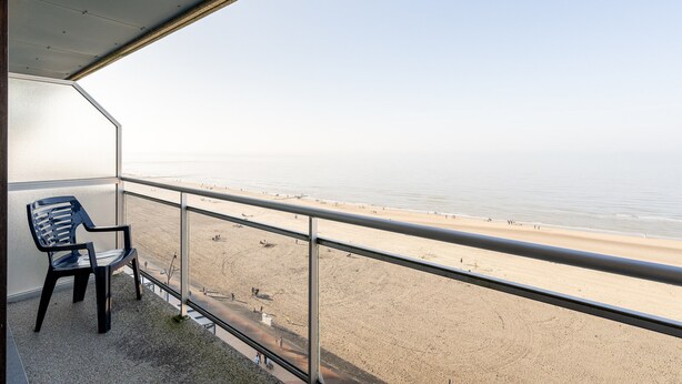 A balcony with a view of a beach, a chair, and a railing. - Apartment in Blankenberge With Sea Views (Blankenberge)