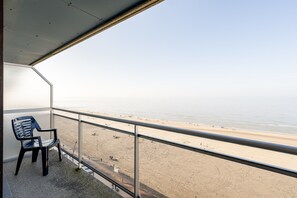 A balcony with a view of a beach, a chair, and a railing. - Apartment in Blankenberge With Sea Views (Blankenberge)