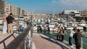 A marina with boats docked, a pedestrian walkway, and buildings in the background. - Apartment in Blankenberge With Sea Views (Blankenberge)