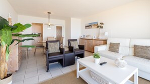 A modern living room with a white sofa, two black armchairs, a white coffee table, and a large green plant. - Apartment in Blankenberge With Sea Views (Blankenberge)