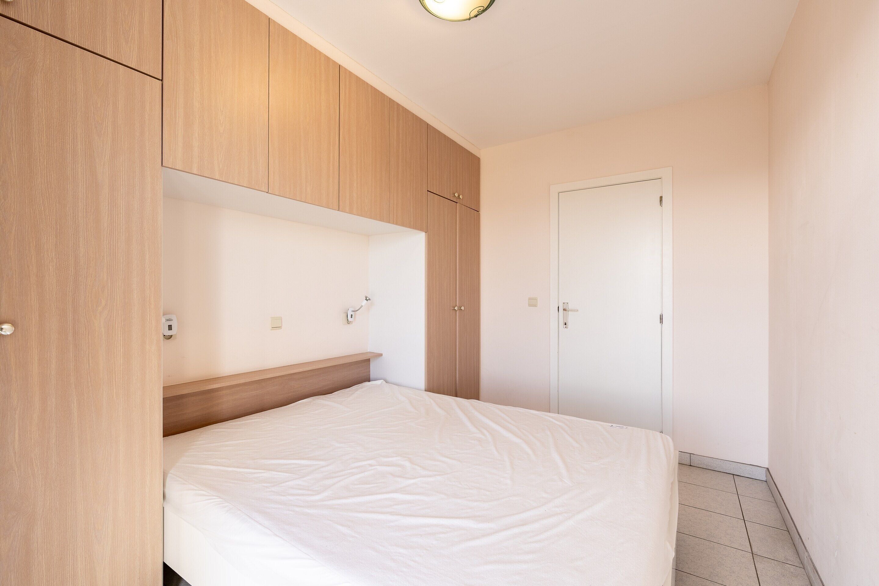 Une chambre à coucher avec un lit, une armoire en bois et une porte blanche.
