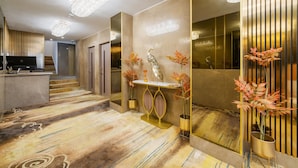 A modern hotel lobby with a reception desk, a decorative console table with vases, and a large mirror reflecting the interior. - Chic & Modern Apartment in Prime Mayfair H2 (London)