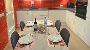 A modern kitchen with white cabinets, red accents, and a dining area set for four. - Villa with private pool (Orihuela Costa)