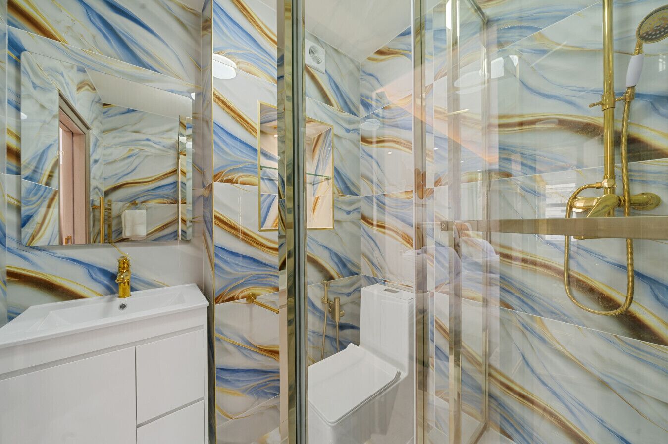 A bathroom with a marble backsplash, a white sink, and a glass shower enclosure.