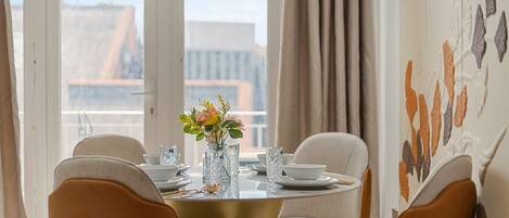 A dining area with a round table, four chairs, and a vase with flowers.