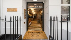 A hallway leading to a door with a sign reading "Hertford Court 14-15". - Luxe Mayfair Two Bedroom with Hotel Finish H5 (London)