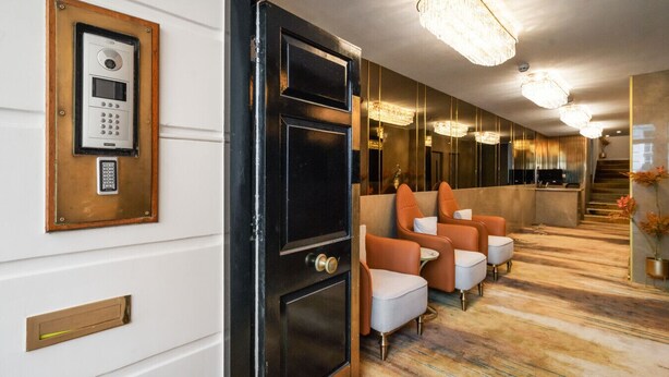 Eine Hotelhalle mit einer Rezeption, einer Sitzgelegenheit und einem Sicherheitstastenfeld an der Wand.