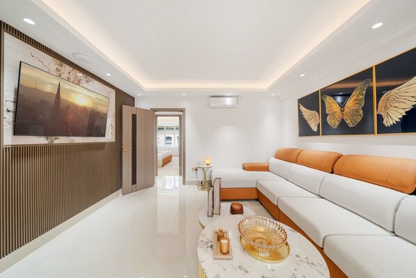 A modern living room with a white sofa, a coffee table, and butterfly wall art. - Modern Mayfair Gem Two Bedroom Apartment H6 (London)