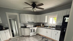 A kitchen with white cabinets, a stove, a microwave, and a ceiling fan. - 3BR, 4-Bed Home in Port Clinton (Port Clinton)