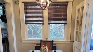 Un comedor con una mesa y sillas de madera, un jarrón decorativo y una lámpara colgante.