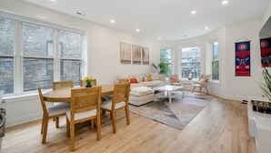 A spacious living room with a dining area, large windows, and a view of the city.