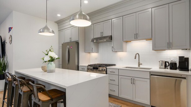 A modern kitchen with a central island, stainless steel appliances, and pendant lighting.