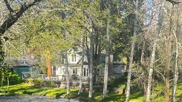A riverside view with a house surrounded by trees and greenery.