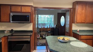 A kitchen with wooden cabinets, a microwave, an oven, and a green countertop.