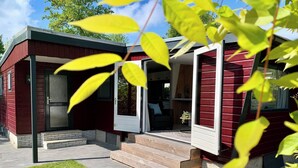 Una casa roja con porche techado y puerta abierta al interior.