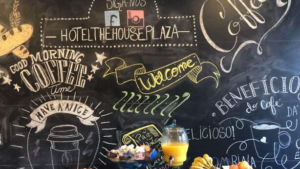 A breakfast setup with a variety of food items and a chalkboard with 'Hotel The House Plaza' written on it. - The House Plaza Hotel (Guarujá)
