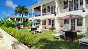 A two-story building with a covered patio area featuring outdoor seating and umbrellas. - Belvedere Holiday Home (St. John's)