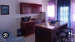 A compact kitchen with a central island, dark wooden cabinets, and a ceiling fan. - Belvedere Holiday Home (St. John's)