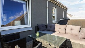 An outdoor patio with a glass-top table, wicker chairs, and a cushioned seating area. - 5 Person Holiday Home in Snedsted (Snedsted)