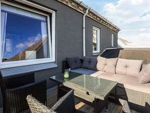 An outdoor patio with a glass-top table, wicker chairs, and a cushioned seating area. - 5 Person Holiday Home in Snedsted (Snedsted)