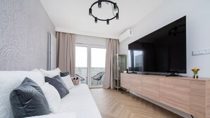 A modern living room with a sofa, TV, and a glass door leading to an outdoor area.