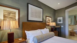 Una habitación de hotel impecable con una cama grande, dos mesitas de noche con lámparas y cuadros en las paredes.
