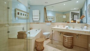 Un baño moderno con cabina de ducha de vidrio, una bañera independiente, un inodoro y un lavabo con espejo.