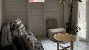 A cozy room with a sofa, a chair, a small table, and a potted plant.