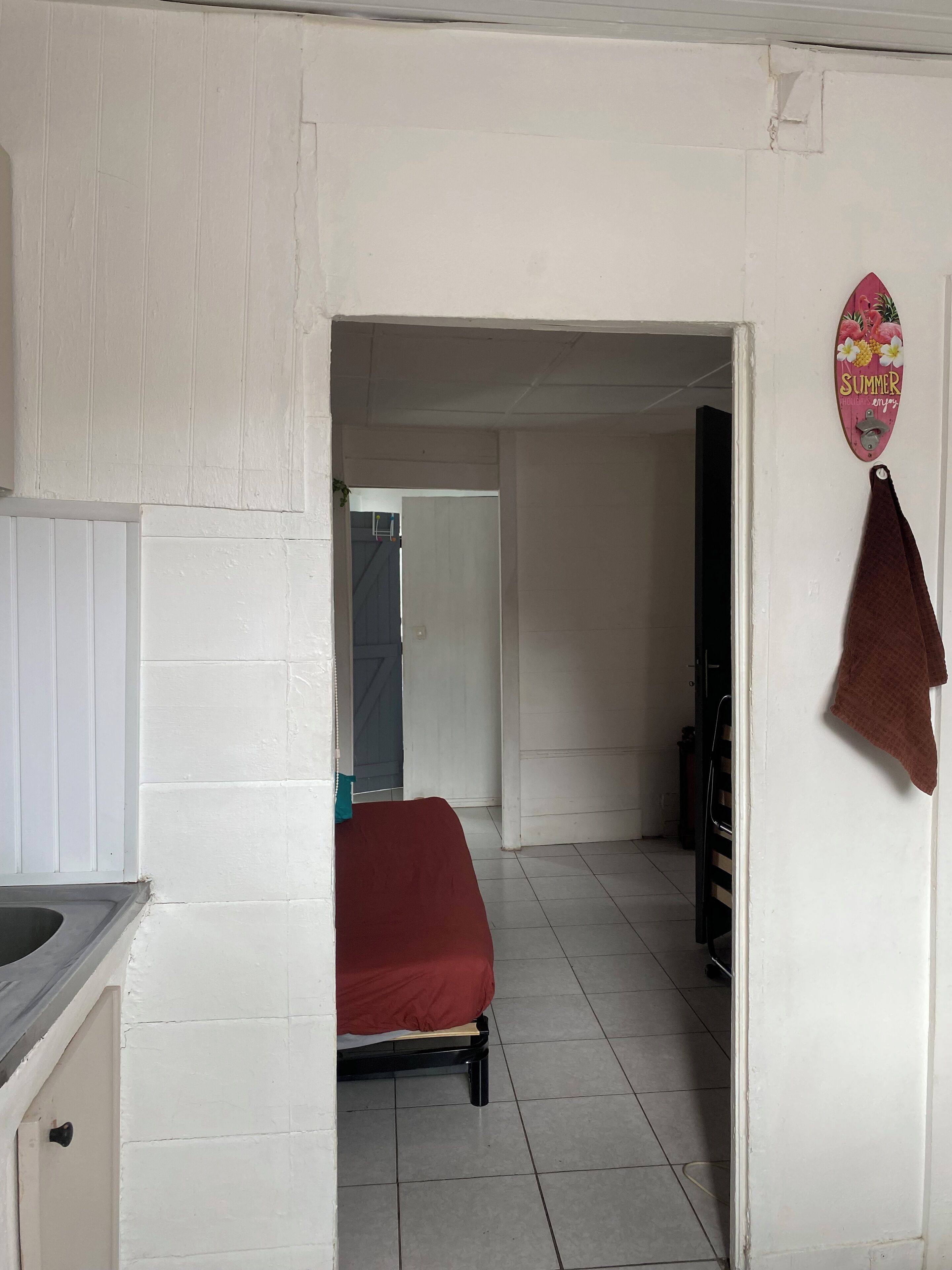 A room with a bed, a white door, and a towel hanging on the wall.
