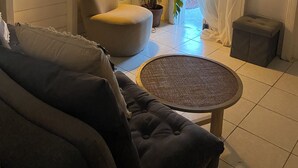 A cozy living room with a sofa, a chair, a small table, and a potted plant.