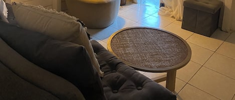 Una sala de estar acogedora con un sofá, una butaca, una mesita y una planta en maceta.