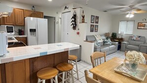 Una cocina moderna con una isla central, taburetes de madera y una mesa de comedor con sillas.