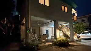 Un edificio de dos pisos con un área de estacionamiento techada y una escalera que lleva a un nivel superior.