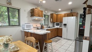 Una cocina con una isla central, armarios de madera, un refrigerador blanco y un ventilador de techo.