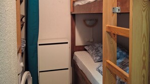 A compact room with a bunk bed, a small white cabinet, and a washing machine.