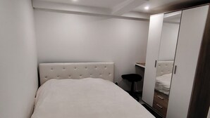 A bedroom with a large bed, a wardrobe, and a mirror.