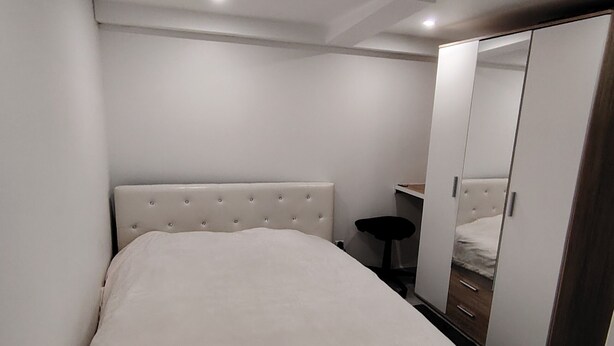 A bedroom with a large bed, a wardrobe, and a mirror.