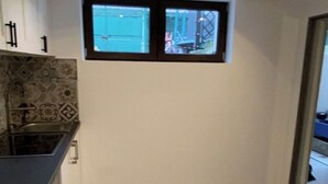 A kitchen with a window, tiled floor, and a sink.