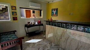A room with a herringbone floor pattern, a wooden bench, a tiled backsplash, and a yellow accent wall. - 🏡 Roots Inn of Porto! Always ready to welcome you with affection💛📍 (Porto de Galinhas Ipojuca)