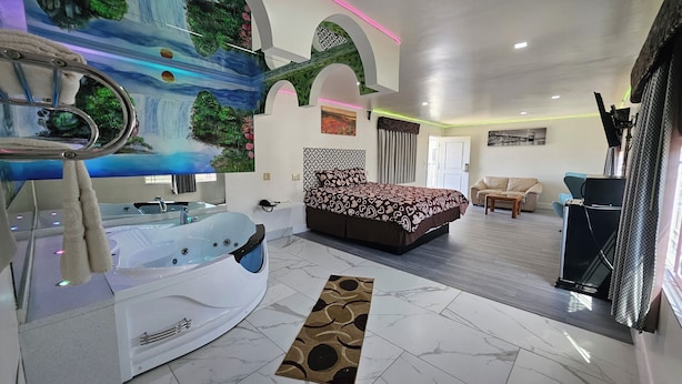 A modern bedroom with a large bed, a jacuzzi, a sofa, and a dining table. - Dream Inn (Inglewood)