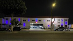 A building with a parking garage entrance, multiple vehicles parked, and a streetlight. - Dream Inn (Inglewood)