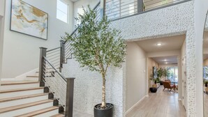 Interior moderno com escada, planta em vaso e área de refeições.