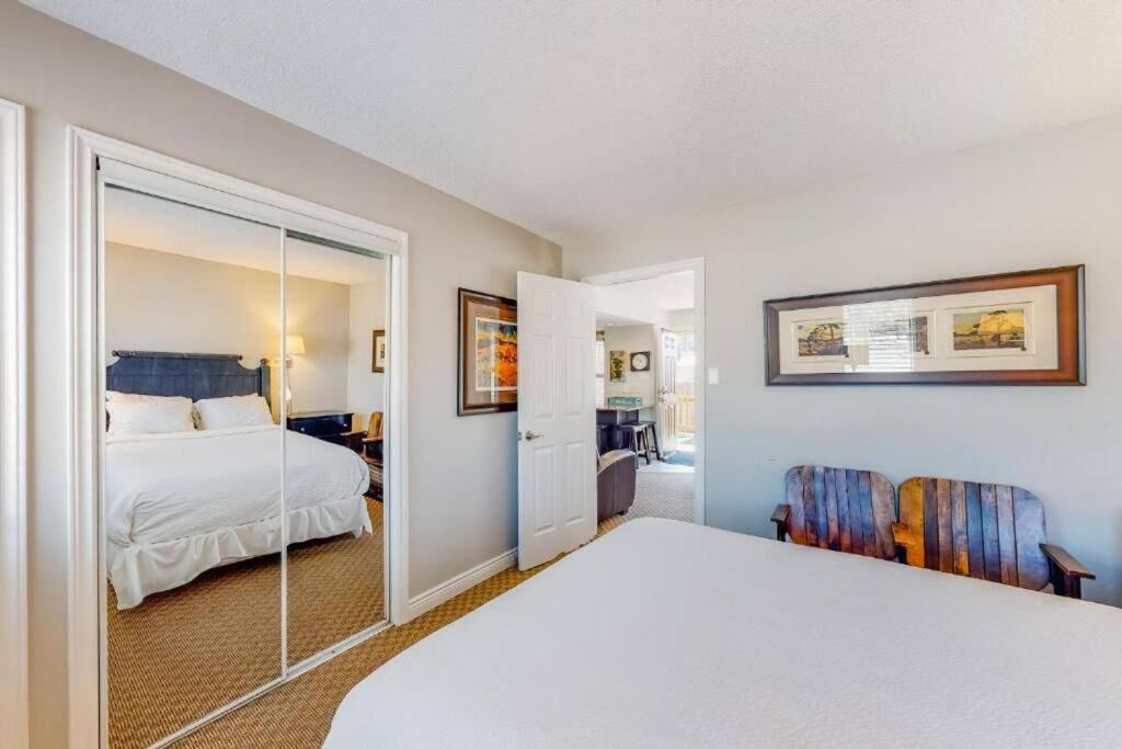 Een hotelkamer met een bed, een spiegel, een stoel en een deur die naar een andere kamer leidt.