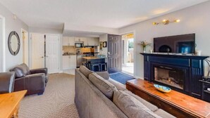 A living room with a fireplace, a sofa, a coffee table, and a television. - Steps to the Hill 1 Bedroom Wifi Crave TV (Blue Mountain)
