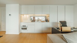 A modern kitchen with white cabinetry, a built-in oven, and a countertop with various appliances and decorations.