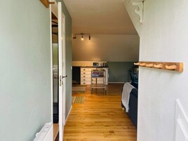 Un pasillo estrecho que conduce a una cocina con microondas, una mesa pequeña y una silla.